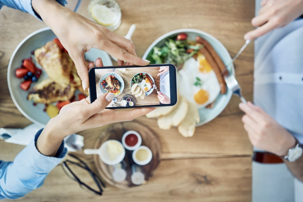 Couple having breakfast and taking photo of their meal